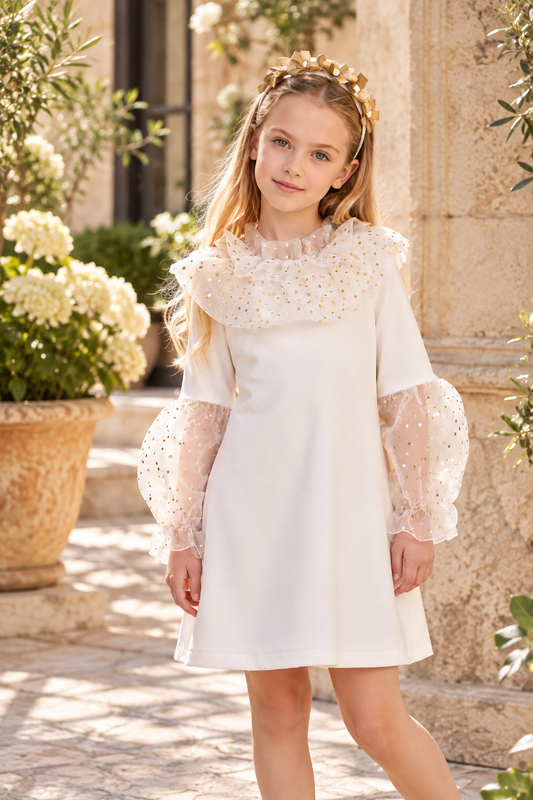 Rochy Gold girls ivory dress with gold spotted tulle collar and puff sleeves, styled in a Spanish courtyard