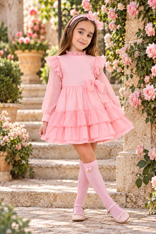 Rochy Rosse girls soft pink chiffon dress with tiered ruffles and waist bow in a rose garden
