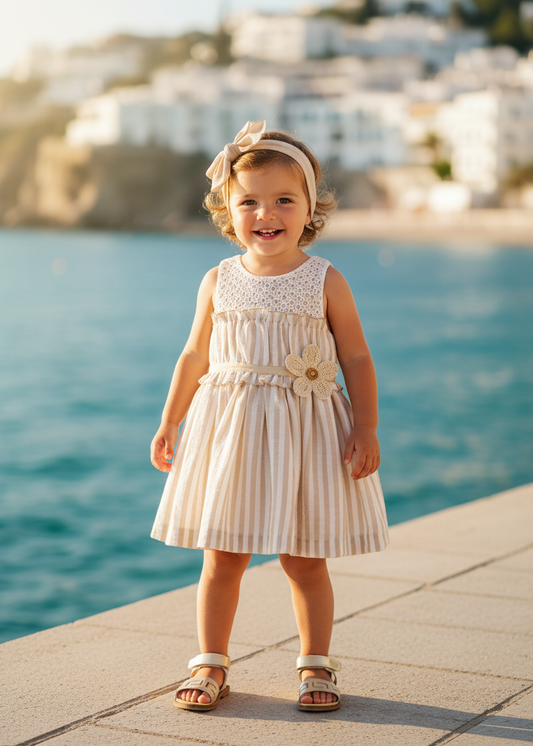 Basmarti Rayas girls beige stripe dress in a seaside setting