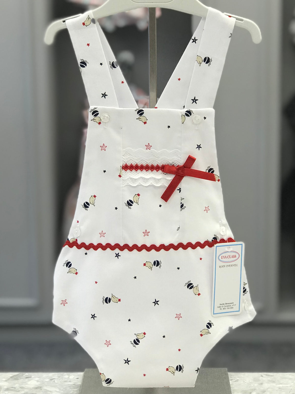 Eva Class Clara girls white romper with navy and red bird and star print, white lace panel, red satin bow and crossover straps